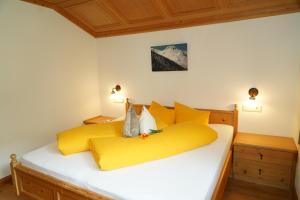 a bedroom with a large bed with yellow sheets at Sesvennahof in Malles Venosta