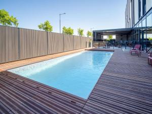 a swimming pool on a building with a wooden deck at ibis Styles Castelnaudary in Castelnaudary