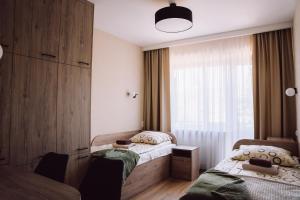 two beds in a room with a window at Sanatorium Dedal in Polańczyk