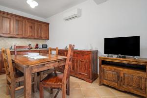 a kitchen with a wooden table and a flat screen tv at Bella Vista su tavolara 4 in Porto San Paolo