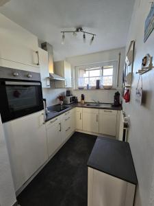a kitchen with white cabinets and a black counter top at Ferienhaus 1260 in Tossens in Tossenserdeich +27 photos