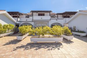 a large white house with trees in a courtyard at Bella Vista su tavolara 4 in Porto San Paolo
