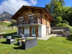 a wooden house with a balcony on the grass at Chez Aless in Ovronnaz