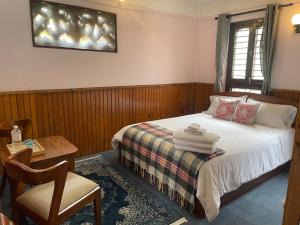 a bedroom with a bed and a table and a chair at Rato Ghar Hotel and Rooftop Restaurant in Bhaktapur