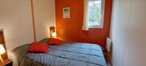 a bedroom with a bed with red pillows and a window at Camping nature 3 étoiles avec piscine - bord de rivière in Chézery-Forens