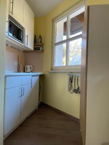 a kitchen with white cabinets and a window at Waldliebe Spiegelhütte - Ferienwohnung am Bach in Lindberg +7 photos