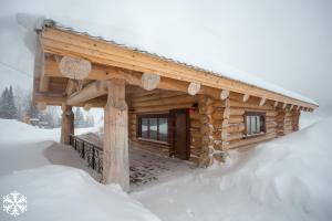 a snow covered cabin with a snow board on top of it at Zima-Leto Hotel in Sheregesh