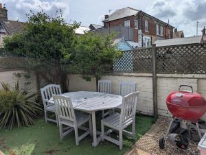 a table and chairs in a backyard with a grill at Spacious 3 bed house near beach! in Lowestoft +6 photos