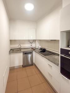 a white kitchen with white cabinets and a dishwasher at Refúgio dos Arrifes in Vila Baleira