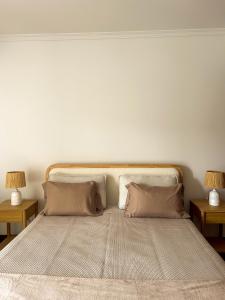 a large bed with two pillows and two tables at Refúgio dos Arrifes in Vila Baleira