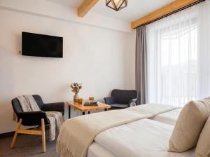 a bedroom with a bed and two chairs and a tv at Golden Apartments - Villa Taternik - Studio with balcony in Zakopane