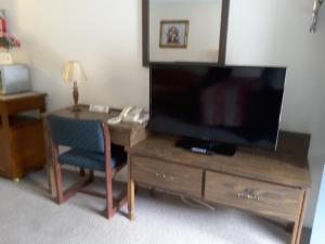 una stanza con una scrivania con una televisione e una sedia di Canyon Alpine Motel a Boston Bar
