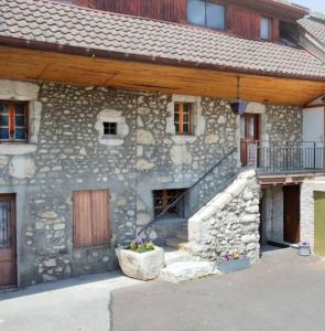 an old stone house with a wooden roof and a porch at Loft Cosy et atypique in Sévrier