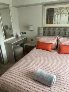 a bedroom with a large bed with orange pillows at Poppy in Ferndown +19 photos