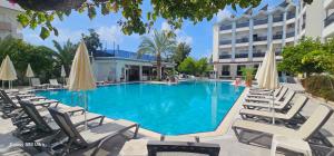 a swimming pool with lounge chairs and umbrellas at Gazipasa Star Otel in Side