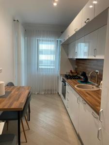 a kitchen with white cabinets and a wooden table at Suite Luxury Pipera and Spa in Bucharest