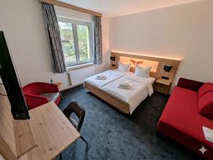 a hotel room with a bed and a red chair at Jagdhotel am Strehlesee in Wandlitz
