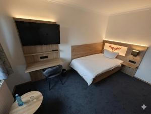 a small room with a bed and a flat screen tv at Jagdhotel am Strehlesee in Wandlitz