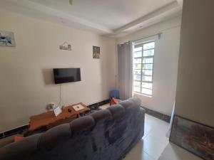 a living room with a couch and a tv at Humble Homes 1 bedroom Thika Town CBD access to Netflix,Fridge,wifi in Thika +15 photos