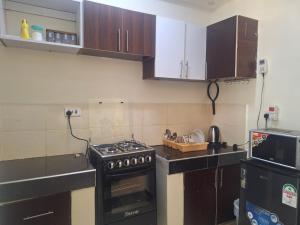 a kitchen with a stove top oven next to a microwave at Humble Homes 1 bedroom Thika Town CBD access to Netflix,Fridge,wifi in Thika