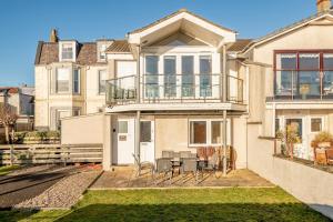 a house with a balcony with a table and chairs at West Cottage - Elie in Earlsferry