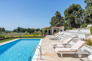 a villa with a swimming pool and lounge chairs at Luxury Villa with Private Pool in Skopelos, Nature Retreat, Villa Pine Trees by Kardous in Alikias