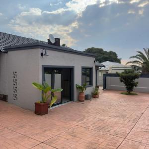 a white house with potted plants on a patio at Cozy Villa Lodge in Edenvale