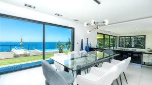 a dining room with a glass table and white chairs at Villa Skylark - by LovelyStay in Ponta do Sol