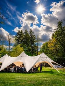 a white tent in a field with a group of people at Glamping Hive by Stream in Víska