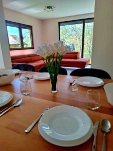 a wooden table with white plates and a vase of flowers at Drina's Heart in Bajina Bašta