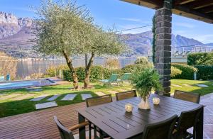 a wooden table and chairs on a patio with a view of the water at Villa Vittoria with private heated pool & shared sauna - Bellagio Village Residence in Oliveto Lario