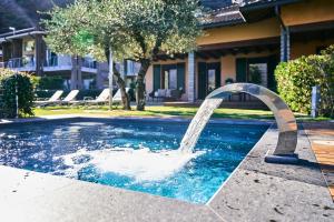 a water fountain in a pool in front of a house at Villa Vittoria with private heated pool & shared sauna - Bellagio Village Residence in Oliveto Lario