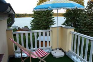 a deck with a chair and an umbrella and an umbrella at Villa am Oberpfuhl in Lychen +8 photos