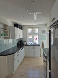 a kitchen with white cabinets and black counter tops at Nybo House in Præstø