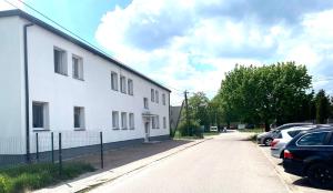 a white building with cars parked in a parking lot at Grądy-Woniecko Place in Grądy