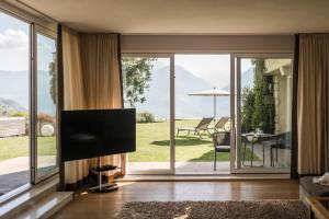 a living room with a tv and sliding glass doors at Schenna Chalet - Chalet Oasis in Schenna