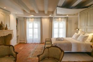 a bedroom with a bed with two chairs and two windows at Chambres d'hôtes de La Tour Morillon in Saint-Amand-Montrond