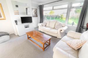 a living room with two white couches and a coffee table at 3-bedroom pet friendly home with off road parking in Swansea