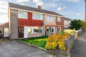 a red brick house with a stone wall at 3-bedroom pet friendly home with off road parking in Swansea