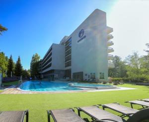 a building with a swimming pool in front of a building at Ensana Esplanade in Piešťany