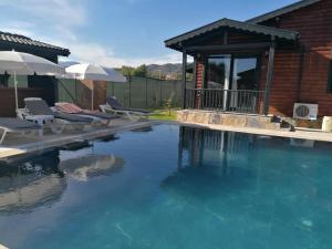 a swimming pool with chairs and umbrellas next to a house at Summertime Bungalows in Fethiye