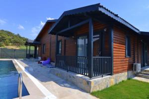 a log cabin with a porch and a swimming pool at Summertime Bungalows in Fethiye
