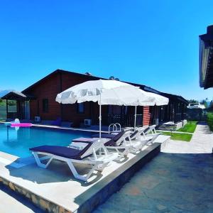 a group of lounge chairs and an umbrella next to a pool at Summertime Bungalows in Fethiye