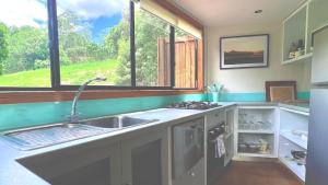 a kitchen with a sink and a large window at Ecoasis Mami Wata in Uki
