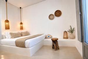 a white bedroom with a bed and a table at Aegeeis in Perissa