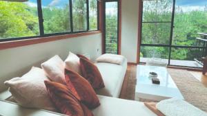 a living room with a couch and a table and windows at Ecoasis Mami Wata in Uki