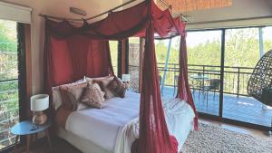 a bedroom with a canopy bed and a balcony at Ecoasis Mami Wata in Uki