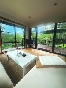a living room with a white table and large windows at Ecoasis Mami Wata in Uki