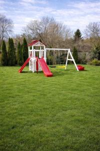 a playground with a red and white swing set in a field at Vila Maria in Râşnov