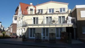a white building with a balcony on a street at Sonneneck in Norderney